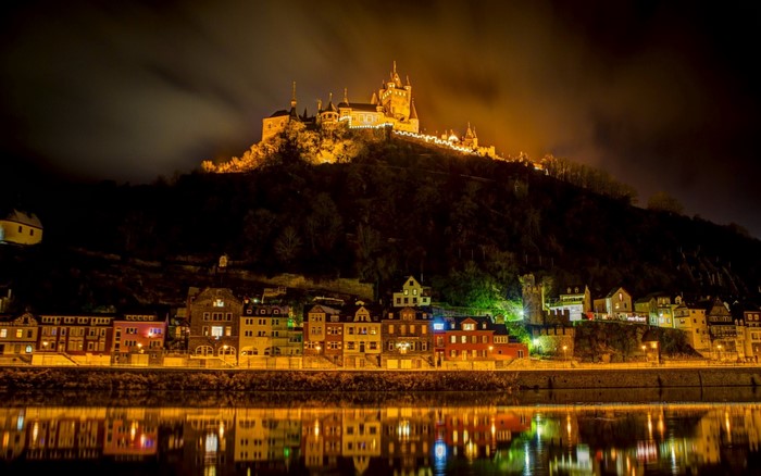 Castle on a hill overlooking a town at night