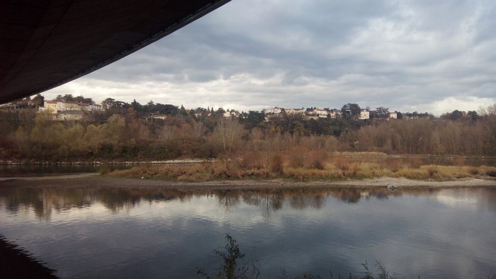 River landscape with town on hill under cloudy sky