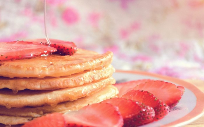 Stack of pancakes with strawberries and syrup