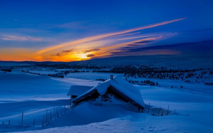 Snowy cabin at sunset with colorful sky
