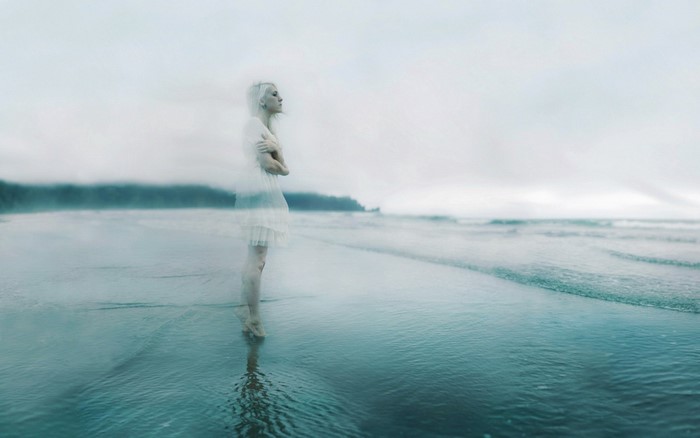 Woman in white dress on a foggy beach