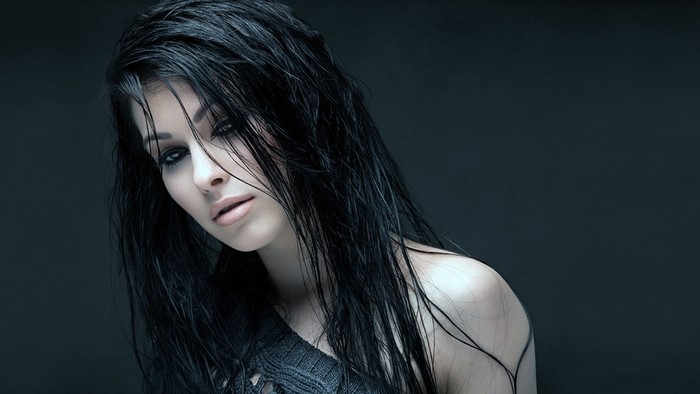 Woman with wet black hair in a dark setting