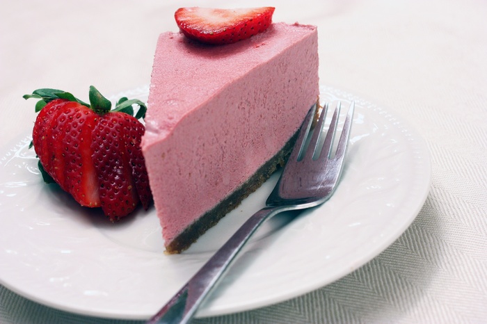 Strawberry cheesecake slice with fork and strawberries