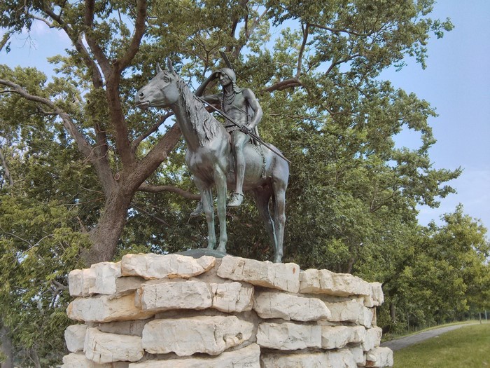 The Scout statue on a stone base in a park