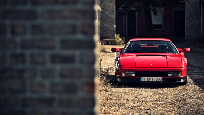 Red Ferrari Testarossa parked on a dirt road