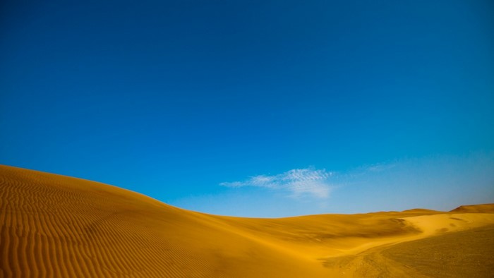 Desert sand dunes under a clear blue sky