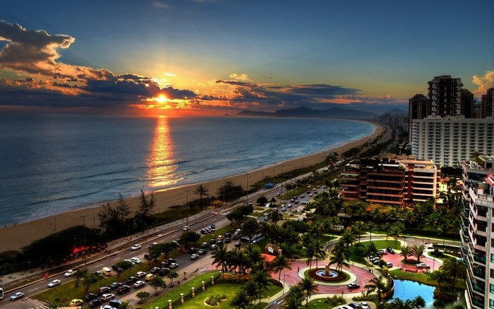 Sunset over a coastal cityscape with a beach and ocean