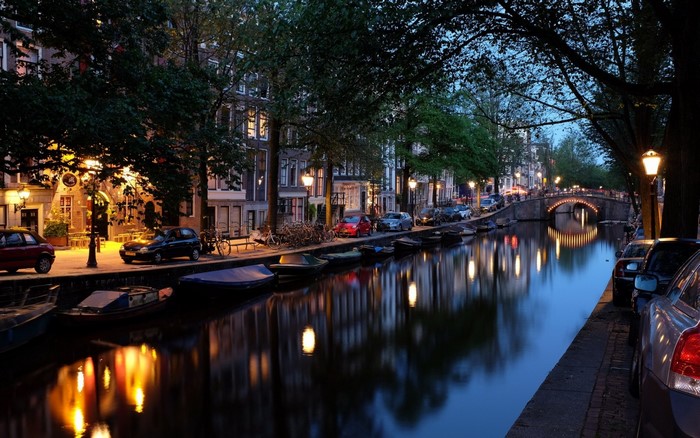 Amsterdam canal at night with illuminated bridge and buildings