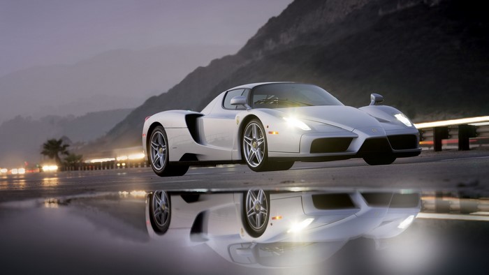 Silver Ferrari Enzo on wet road with mountain background