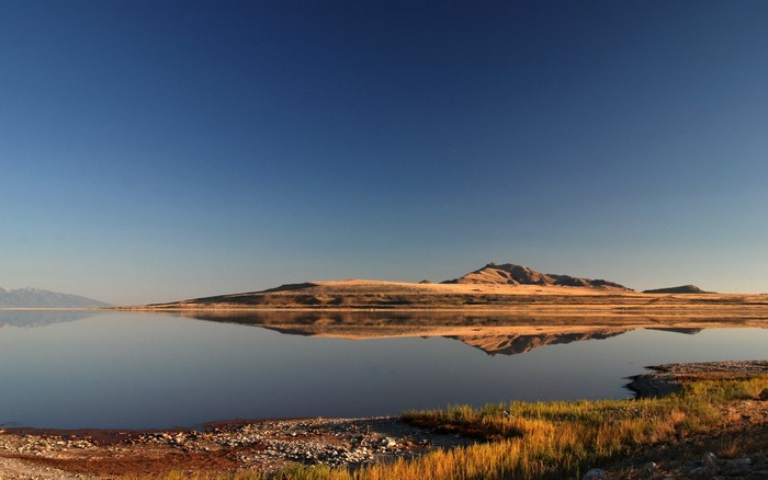 Vast lake reflecting hills under a clear blue sky