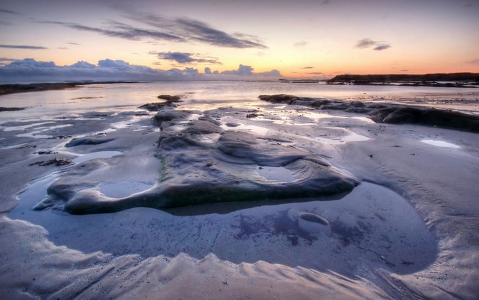 Beach at sunset with rock formations and tide pools