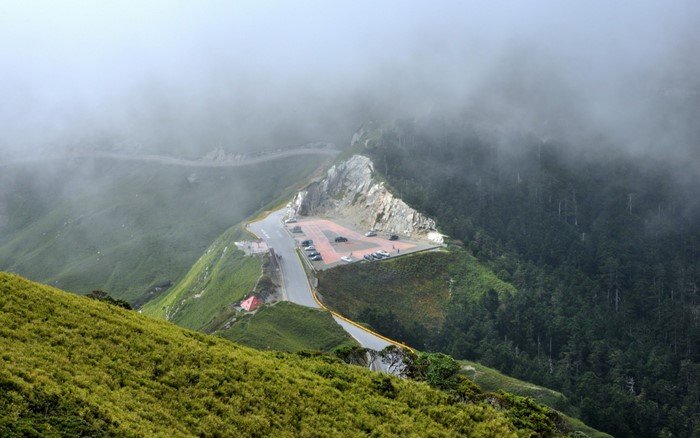 Mountain road with parking lot and forest in fog
