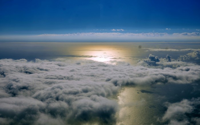Aerial view of clouds over the ocean with sunlight reflection