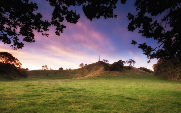 Hilltop monument at sunset with silhouetted trees