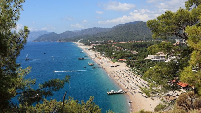 Beach resort with turquoise sea and forested mountains