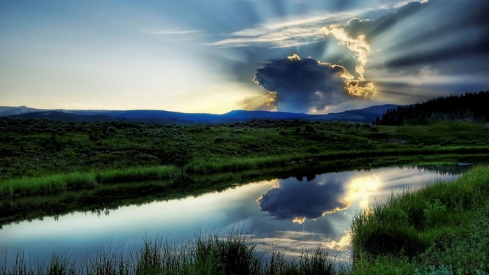 Sunlight breaking through clouds over a lake and landscape