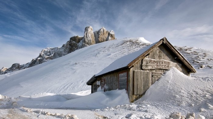 Wooden cabin in the snow with Dolomite mountains