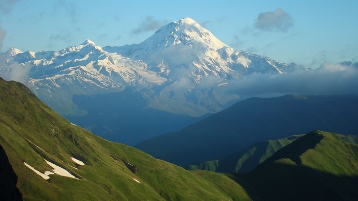 Snow-capped mountain range with green hills