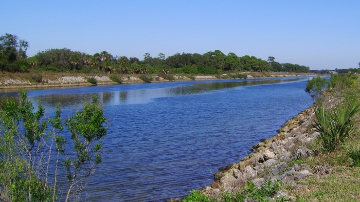 Canal with rocky banks and trees under a clear sky