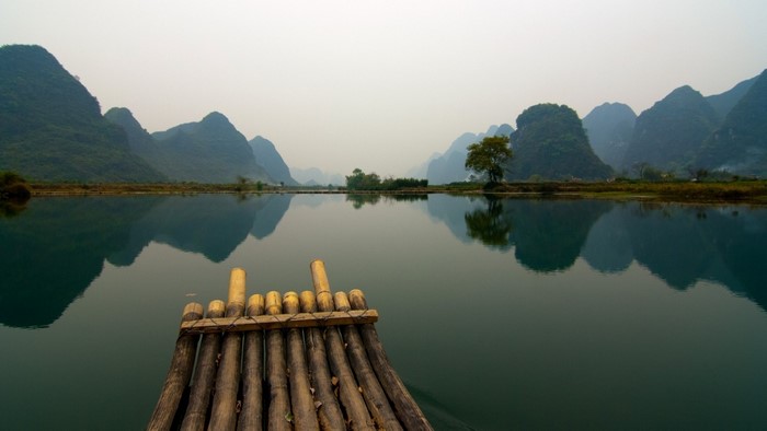 Bamboo raft on a misty river with karst mountains