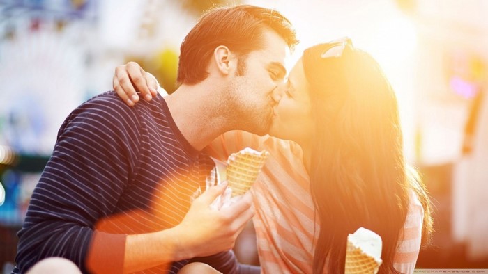 Couple kissing while eating ice cream during golden hour