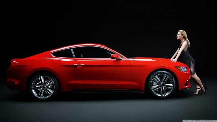 Woman leaning on a red Ford Mustang