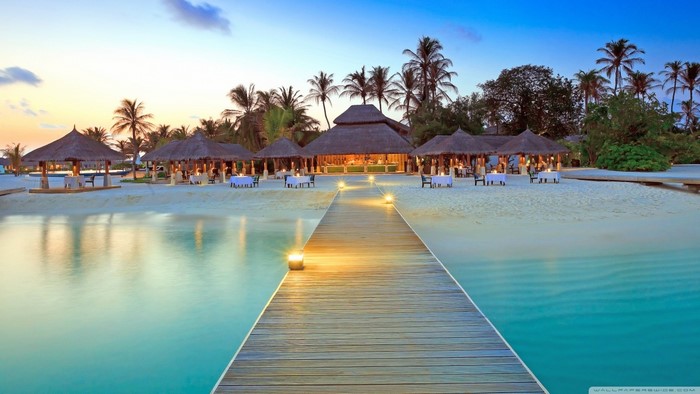 Tropical resort with beachside dining and pier at sunset