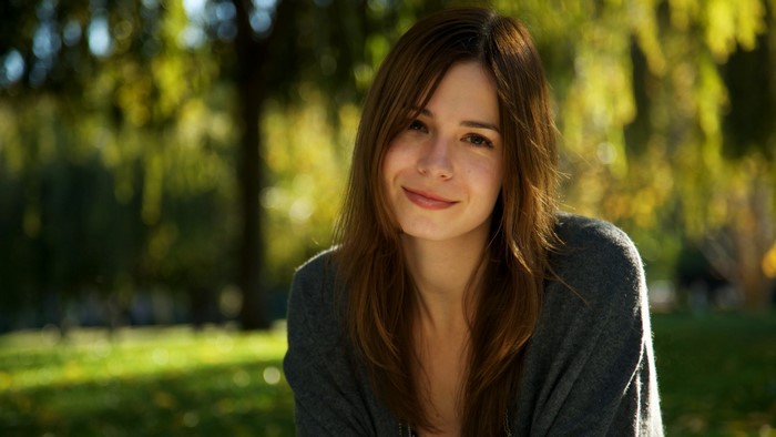 Woman with brown hair smiling in a park