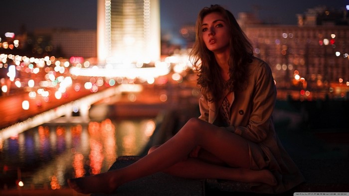 Woman sitting at night with city lights in the background
