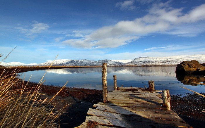 Wooden pier on a calm lake with snow-capped mountains