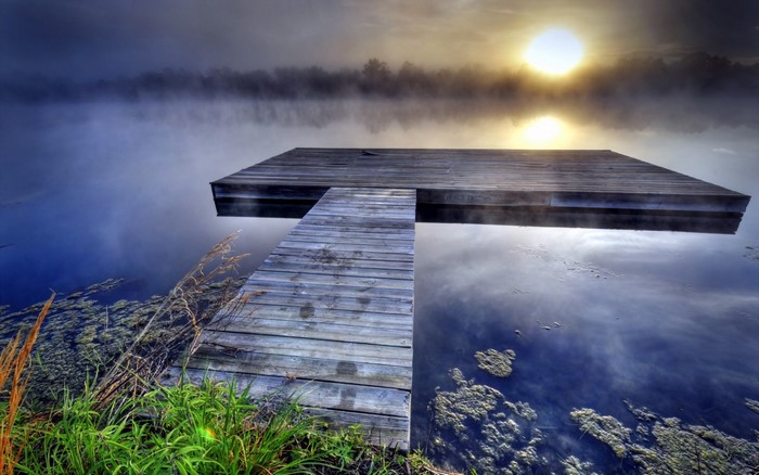 Wooden pier on a misty lake at sunrise