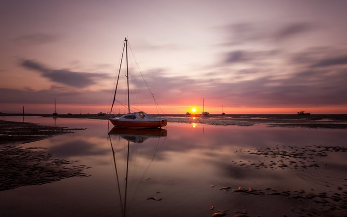 Sailboat on a calm sea at sunset with reflections