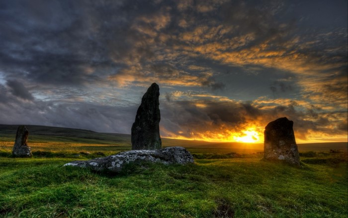 Standing stones at sunset on a grassy hill