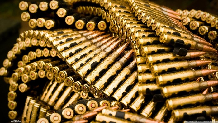 Close-up of a belt of golden ammunition with water drops