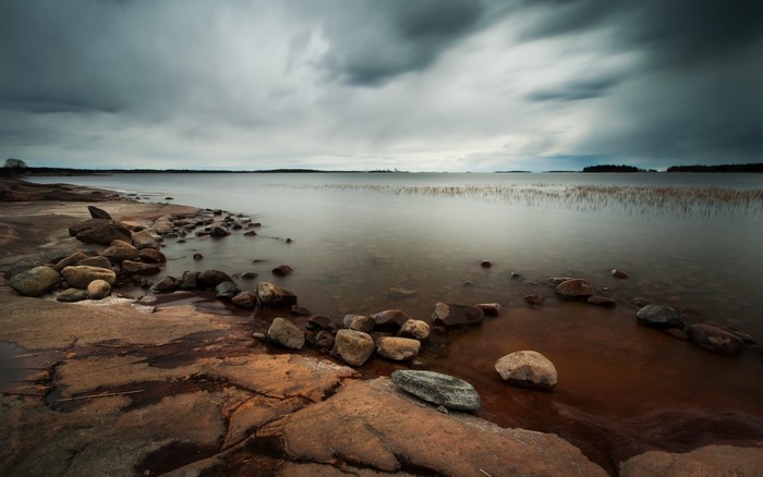 Rocky shore of a calm lake under cloudy skies