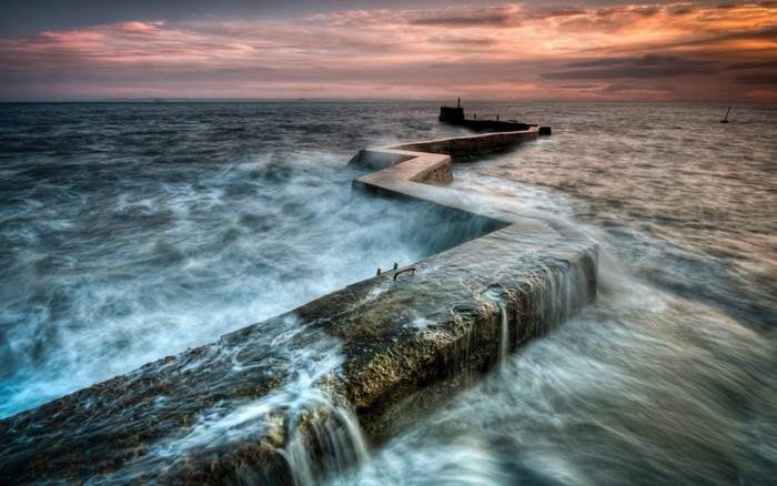 Zigzag concrete pier in the sea at sunset