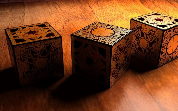 Three Lament Configuration puzzle boxes on a wooden surface