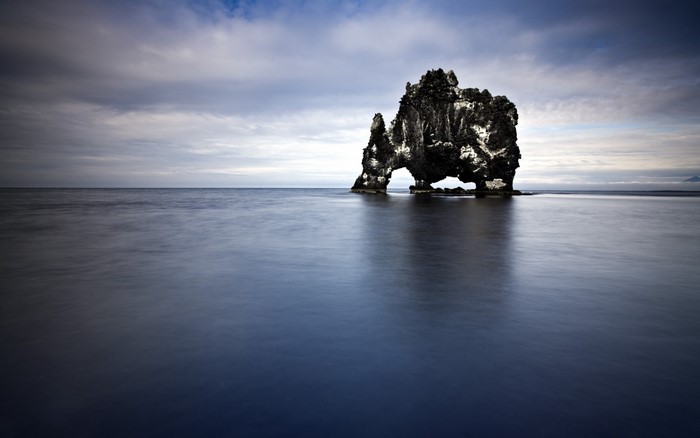 Rock formation in the ocean under a cloudy sky
