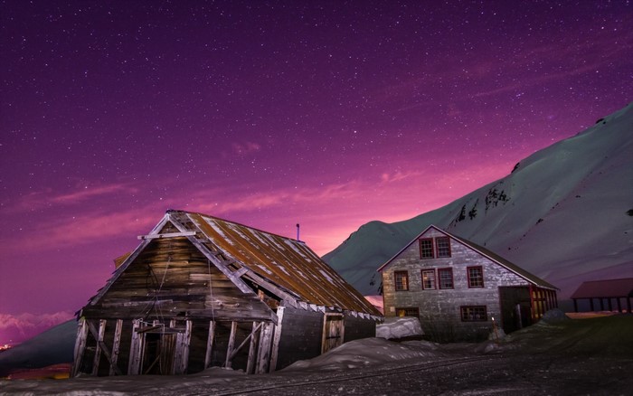 Wooden barn and house under starry purple sky