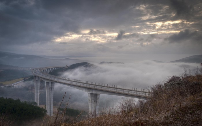 Bridge over misty valley at sunrise
