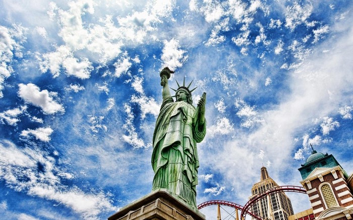 Statue of Liberty replica with roller coaster and buildings