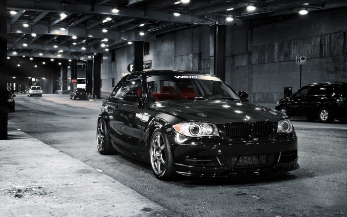 Black BMW coupe with red interior parked on city street