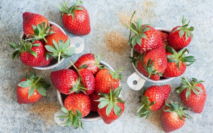 Strawberries in measuring cups with sugar