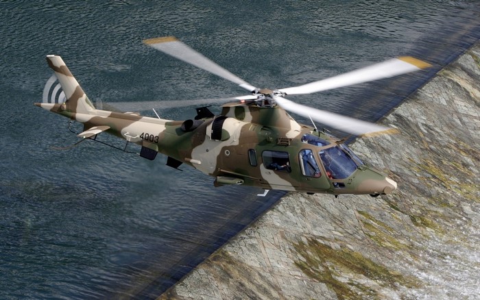 Military helicopter with camouflage pattern flying over water