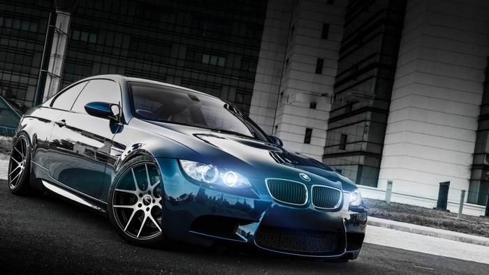 Blue BMW M3 Coupe parked in front of modern buildings