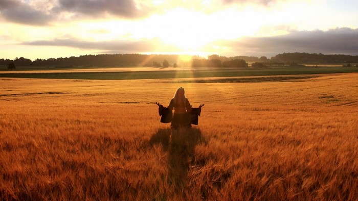 Woman meditating in a wheat field at sunset