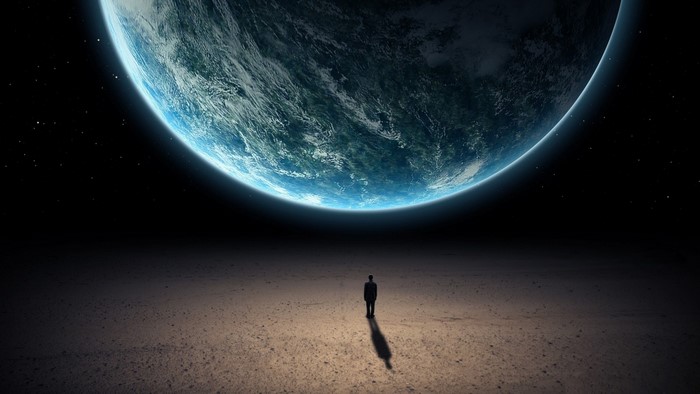 Man standing on a barren planet looking at Earth