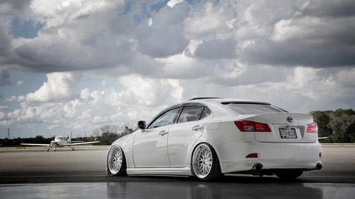 White Lexus IS on tarmac with small airplane