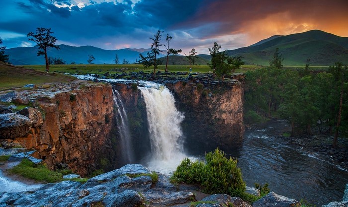 Waterfall cascading over a rocky cliff in a mountainous landscape