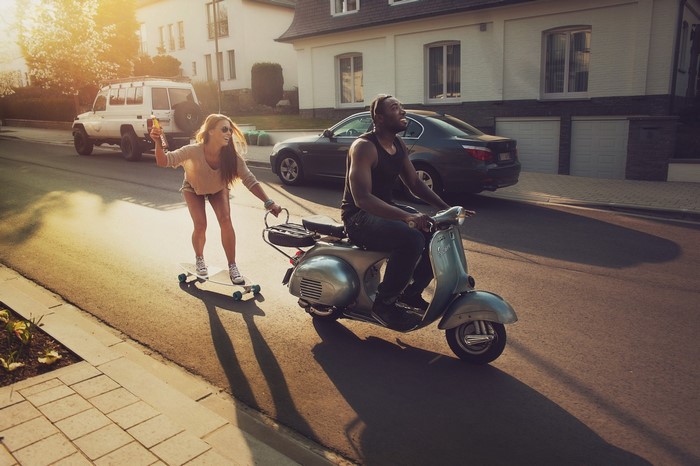 Couple on a scooter and skateboard on a street